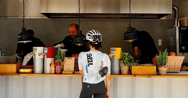 Gast im Radtrikot bestellt am Tresen beim Streetfood Catering von Markus Grein