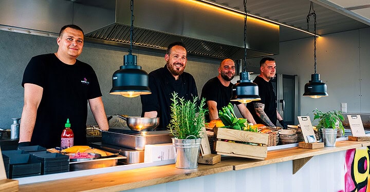 Team von Markus Grein hinter der Theke beim Streetfood Catering mit frischen Kräutern in der Küche