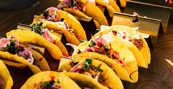 Reihe gefüllter Tacos mit frischen Toppings beim Streetfood Catering angerichtet