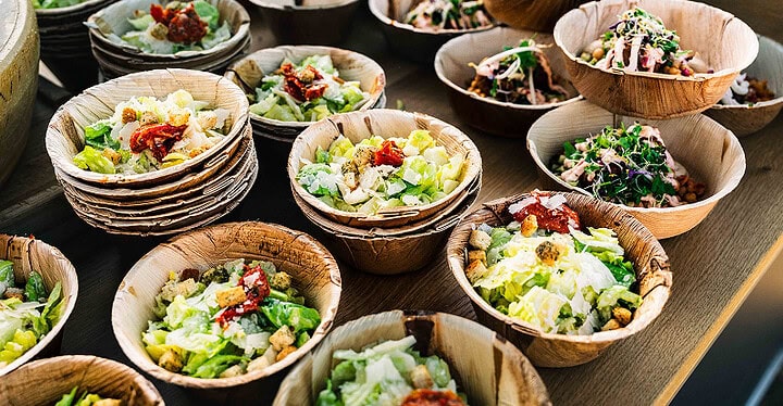 Viele Salat Bowls in Palmblattschalen angerichtet beim Foodtruck Catering für Gäste