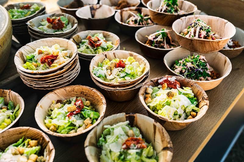 Viele Salat Bowls in Palmblattschalen angerichtet beim Foodtruck Catering für Gäste