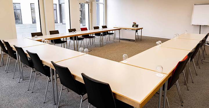 Heller Tagungsraum im Novum Conference & Events mit Bestuhlung in U-Form und Blick auf den Tisch der Tagungsleitung.