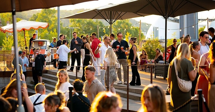 Viele Gäste auf der Terrasse der Würzburger Eventlocation Maschinenhaus bei einem DJ-Event von vamos. und Aperol.