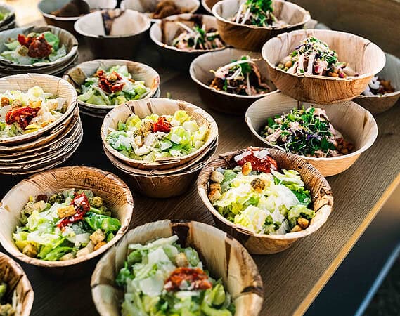 Viele kleine Schalen mit frischen veganen Salaten und Bowls auf einem Tablett bei einem vegenen Catering
