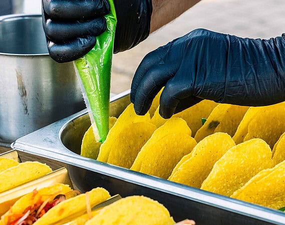 Vegan Sauce wird in frische Taco-Schalen gefüllt bei der Zubereitung bei einem veganen Catering