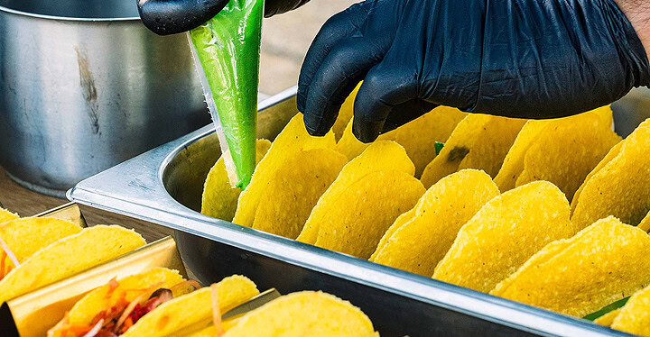 Vegan Sauce wird in frische Taco-Schalen gefüllt bei der Zubereitung bei einem veganen Catering