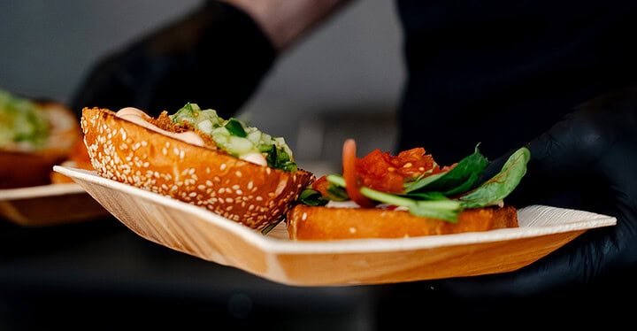 Veganer Burger wird sorgfältig auf einem kleinen Holztellerchen angerichtet