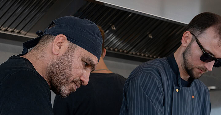 Zwei Köche bereiten in einem Foodtruck Streetfood zu